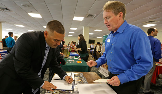 Ignacio Yanes writes information given by Jim Brooks of the Small Business Administration at the annual Veterans Career and Resource Fair in Miami, Florida, February 2015. (AP/Alan Diaz)