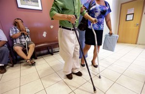 A man using two canes is helped in the waiting area at Nuestra Clinica Del Valle in San Juan, Texas. (AP/Eric Gay)