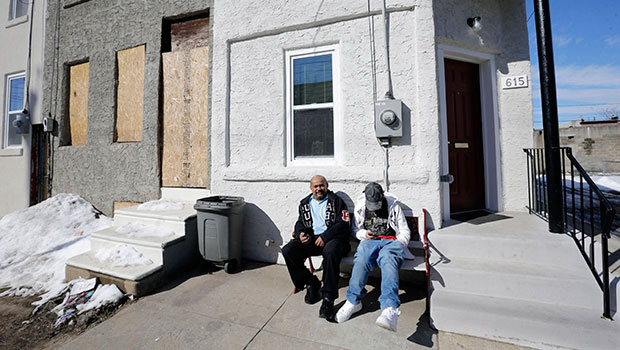Family members sit in front of their refurbished home in Camden, New Jersey, February 23, 2015. (AP/Mel Evans)