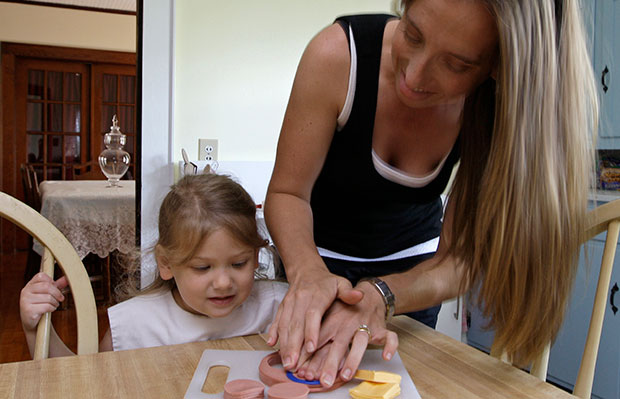 Lilly Hovis, 3, gets some help from her mother, Michelle, as they cut lunch meat into shapes for a picnic at their home in Iron Station, North Carolina, June 2008. (AP/Chuck Burton)