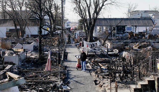 Louise McCarthy carts belongings from her flood-damaged home in the Breezy Point neighborhood of Queens, New York, after Hurricane Sandy. (AP/Mark Lennihan)