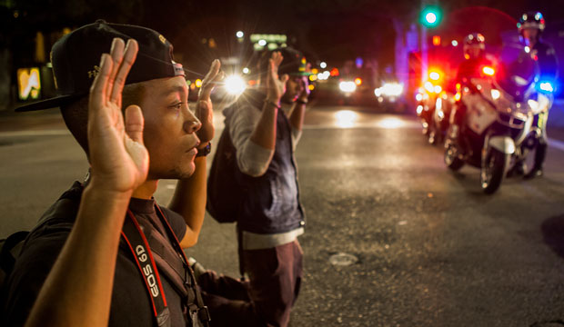 Protesters kneel down with their hands up in front of police officers in Los Angeles, California, on November 26, 2014. (AP/Damian Dovarganes)