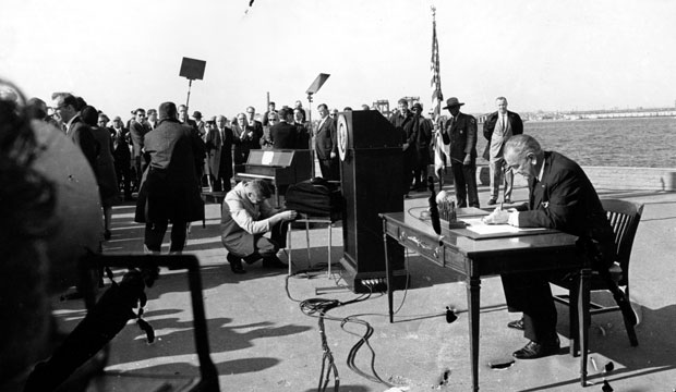 President Lyndon B. Johnson sits at his desk on Liberty Island in New York Harbor as he signs a new immigration bill, October 1965. (Associated Press)