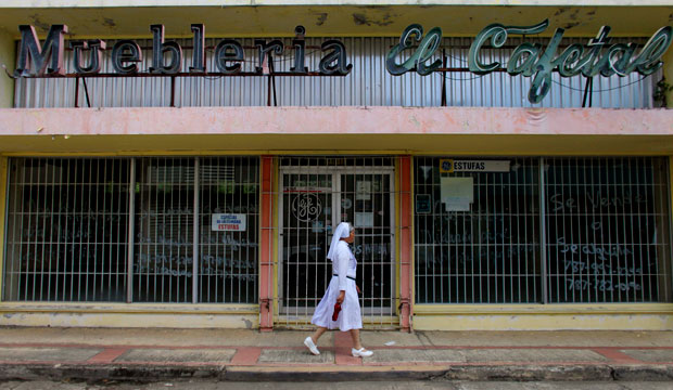 A nun walks in front of a closed furniture store in Lares, Puerto Rico, on September 2, 2015. (AP/Ricardo Arduengo)