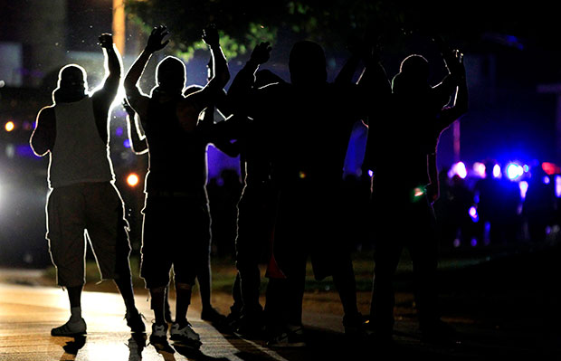 People raise their hands in the middle of the street as police wearing riot gear move toward their position in an attempt to get them to disperse, Monday, August 11, 2014, in Ferguson, Missouri. (AP/Jeff Roberson)