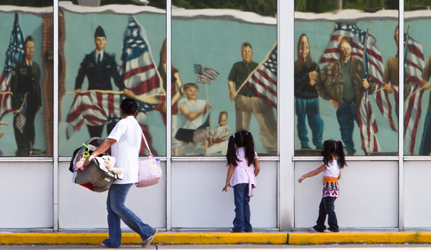 Members of a Latino family walk past a reflection of a patriotic mural in Fremont, Nebraska, on July 21, 2010. (AP/Nati Harnik)