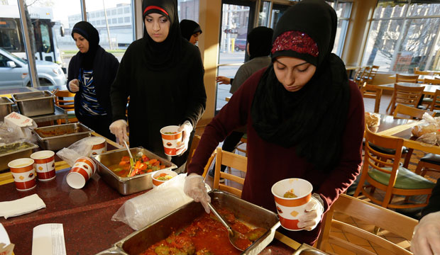 Volunteers Zahraa Debaja, center, and Zeinab Makki, right, prepare meals from food provided by charitable organizations in Dearborn, Michigan, on April 25, 2014. (AP/Carlos Osorio)