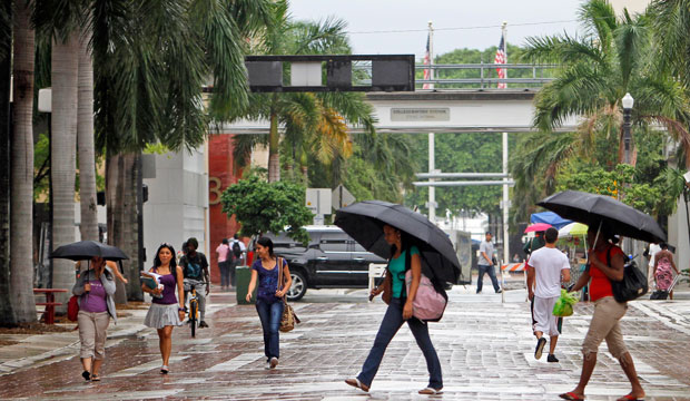 Pedestrians cover themselves from the rain in Florida on July 14, 2010. (AP/Alan Diaz)