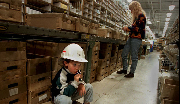 A child takes a sucker break while his mother finishes filling orders during her job as a material handler, April 1997. (AP/Erwin Gebhard)