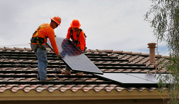 Two electricians install solar panels on a roof in Goodyear, Arizona, on July 28, 2015. (AP/Matt York)