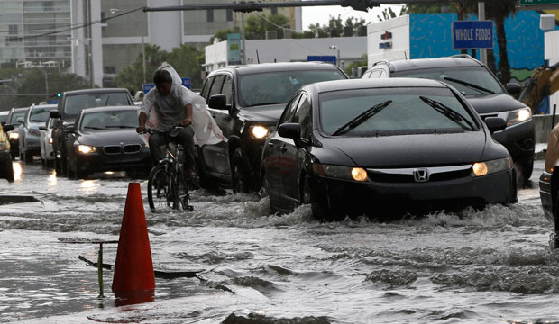 A cyclist and vehicles negotiate heavily flooded streets as rain falls, September 23, 2014, in Miami Beach, Florida. (AP/Lynne Sladky)