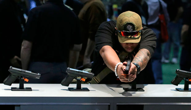 A buyer checks out various hand guns on display during the Shooting, Hunting, and Outdoor Trade Show on January 14, 2014, in Las Vegas. (AP/Julie Jacobson)