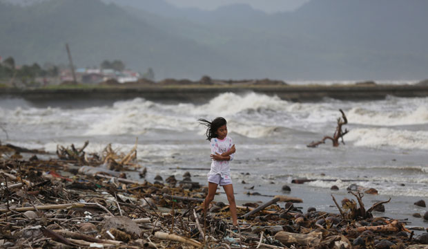 A girl walks along the shore as strong waves from Typhoon Hagupit hit Atimonan in the eastern Philippines on December 6, 2014. (AP/Aaron Favila)