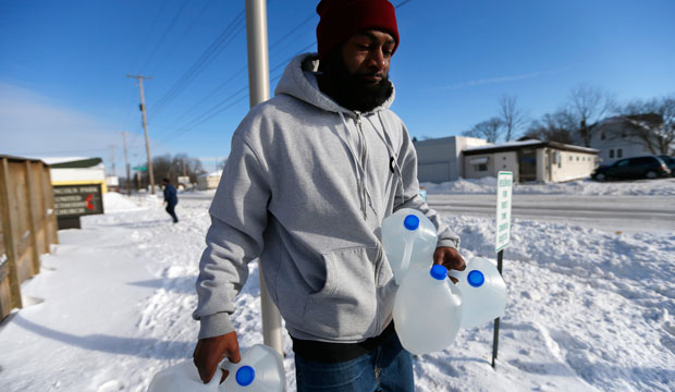 In this February 3, 2015, photo, Lemott Thomas carries free water being distributed at the Lincoln Park United Methodist Church in Flint, Michigan. (AP/Paul Sancya)