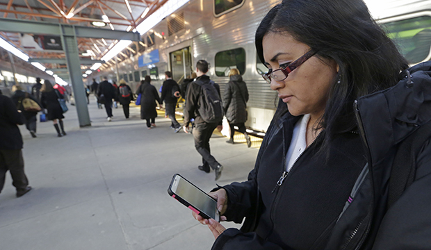 A woman checks a news website on her smartphone before boarding a train home at the end of her workweek in Chicago, March 2015. (AP/M. Spencer Green)