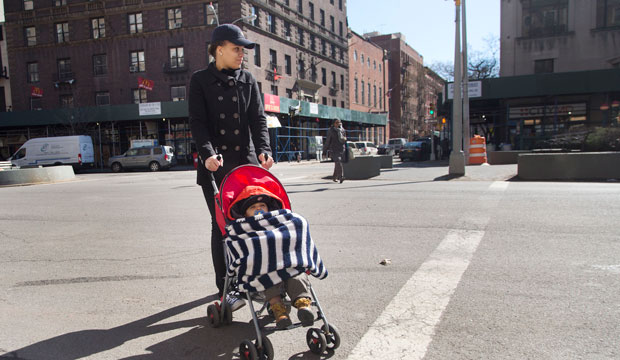 Beonca Williams crosses the street with her 1-year-old son Joshua Felix outside the Regent Family Residence, left, March 12, 2015, in New York. (AP/Mark Lennihan)