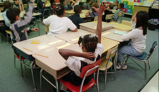 Third-grade students raise their hands at James Curley Elementary School in the Jamaica Plain neighborhood of Boston. (AP/Jay Malonson)