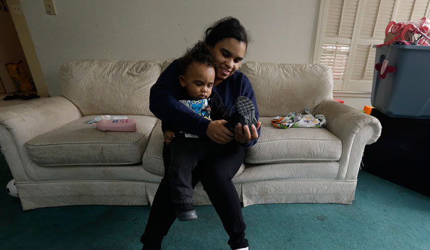 A woman gets her son dressed before leaving home for her job in Sacramento, California, on May 15, 2015. (AP/Rich Pedroncelli)