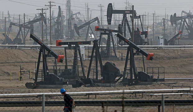 A person walks past pump jacks operating at the Kern River Oil Field in Bakersfield, California, on January 16, 2015. (AP/Jae C. Hong)