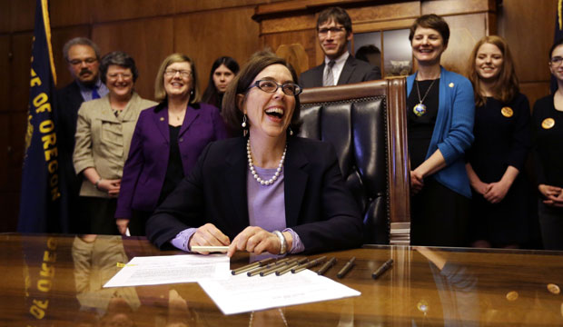 Oregon Gov. Kate Brown (D) smiles after signing an automatic voter registration bill in Salem, Oregon, on March 16, 2015. (AP/Don Ryan)
