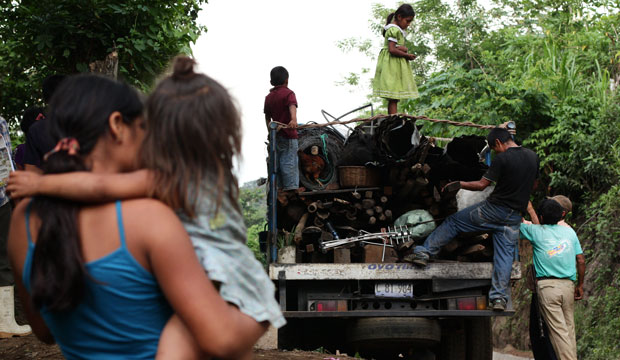 A woman holds a baby as they watch a family leave their community of Tunamiles in Sonsonate Department, El Salvador, May 2016. (AP/Salvador Melendez)