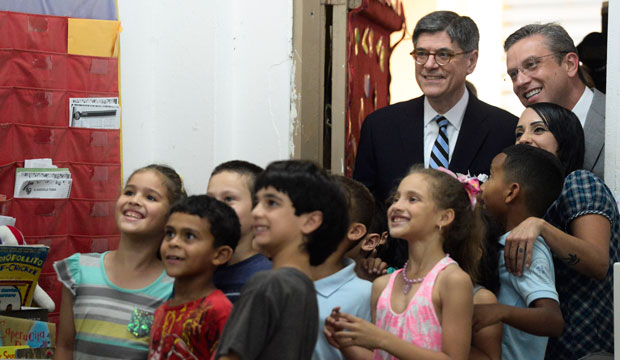 U.S. Treasury Secretary Jacob Lew, top left, poses for photos with students accompanied by Puerto Rico Gov. Alejandro Garcia Padilla, top right, at an elementary school in San Juan on May 9, 2016. (AP Photo/Carlos Giusti)