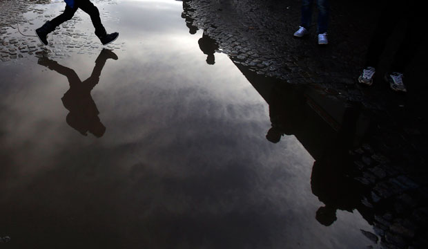 A migrant child jumps over a puddle in Sid, Serbia, on January 11, 2016. (AP/Darko Vojinovic)