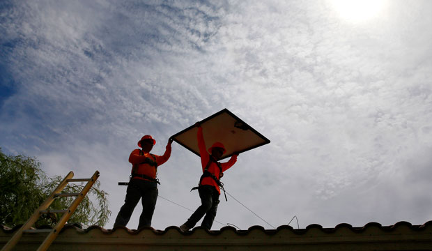Electricians install solar panels on a roof in Goodyear, Arizona, on July 28, 2015. (AP/Matt York)