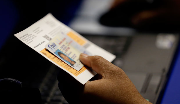 An election official checks a voter's photo identification at a polling site in Austin, Texas, on February 26, 2014. (AP/Eric Gay)