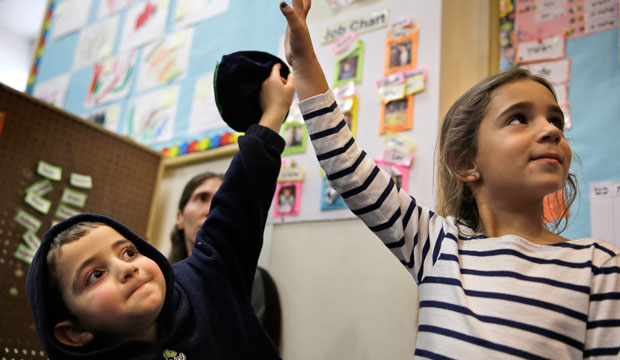 Two children raise their hands in class, March 2015. (AP/Seth Wenig)