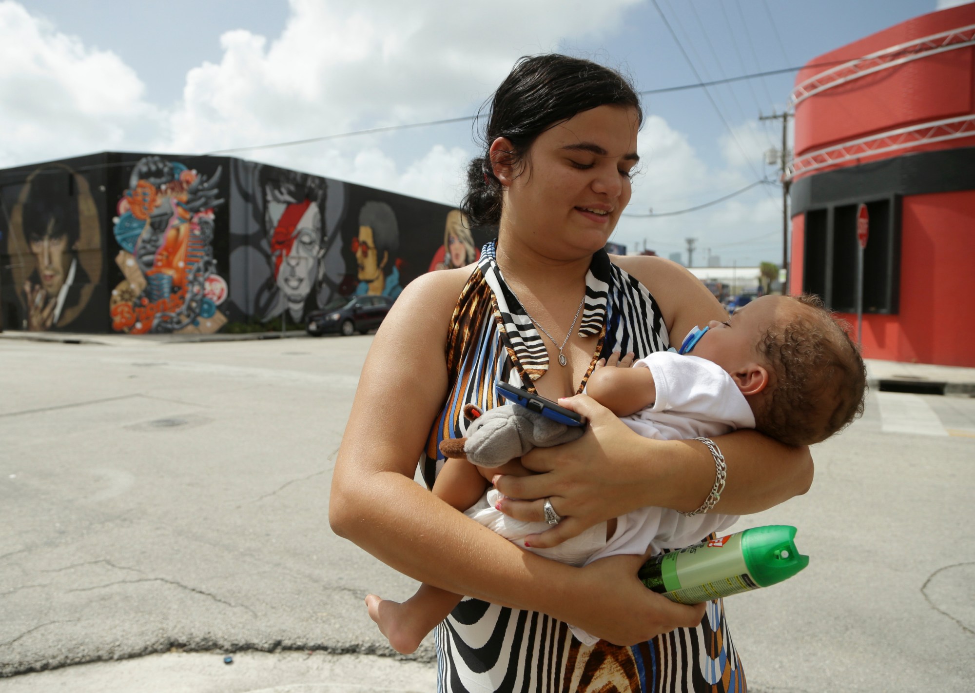 A woman holds her son and a can of insect repellent in the Wynwood neighborhood of Miami on August 2, 2016. (AP/Lynne Sladky)