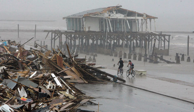 Cyclists ride past debris piled along on the seawall road in Galveston on September 14, 2008, after Hurricane Ike hit the Texas coast. (AP/Matt Slocum)