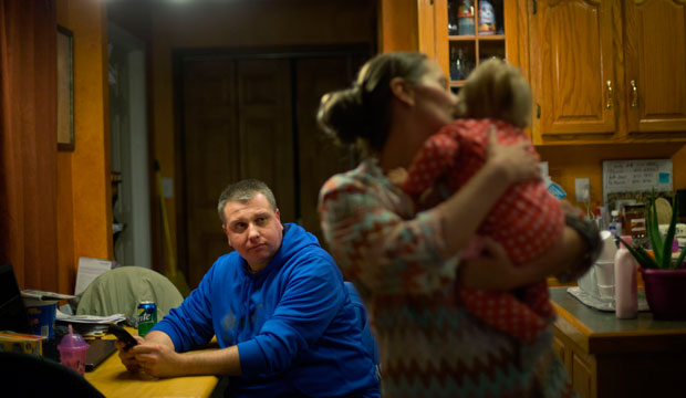 A man sits at the kitchen table as his wife holds their daughter in Harlan, Kentucky, on October 18, 2014. (AP/David Goldman)