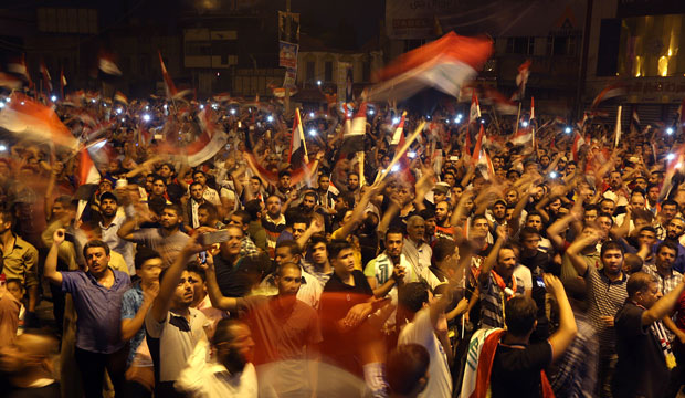 Protesters wave national flags during a demonstration in Tahrir Square in Baghdad, Iraq, on October 2, 2015. (AP/Hadi Mizban)