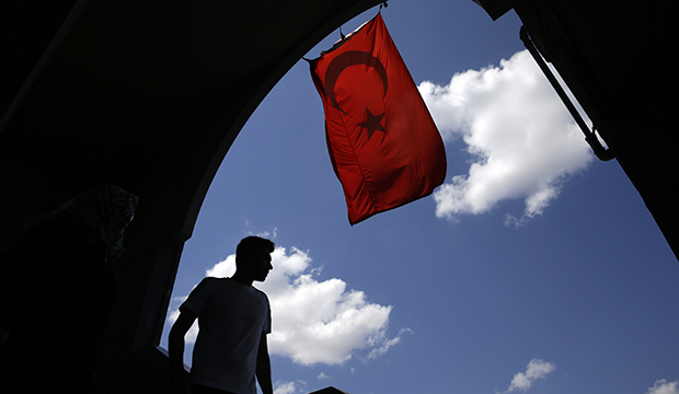 A pedestrian passes under a Turkish flag in Istanbul, August 14, 2016. (AP/Thanassis Stavrakis)