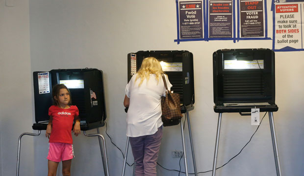 A young girl waits as a voter casts her ballot in the Republican and Democratic primaries at a polling station at the Miami Beach City Hall, March 2016. (AP/Wilfredo Lee)