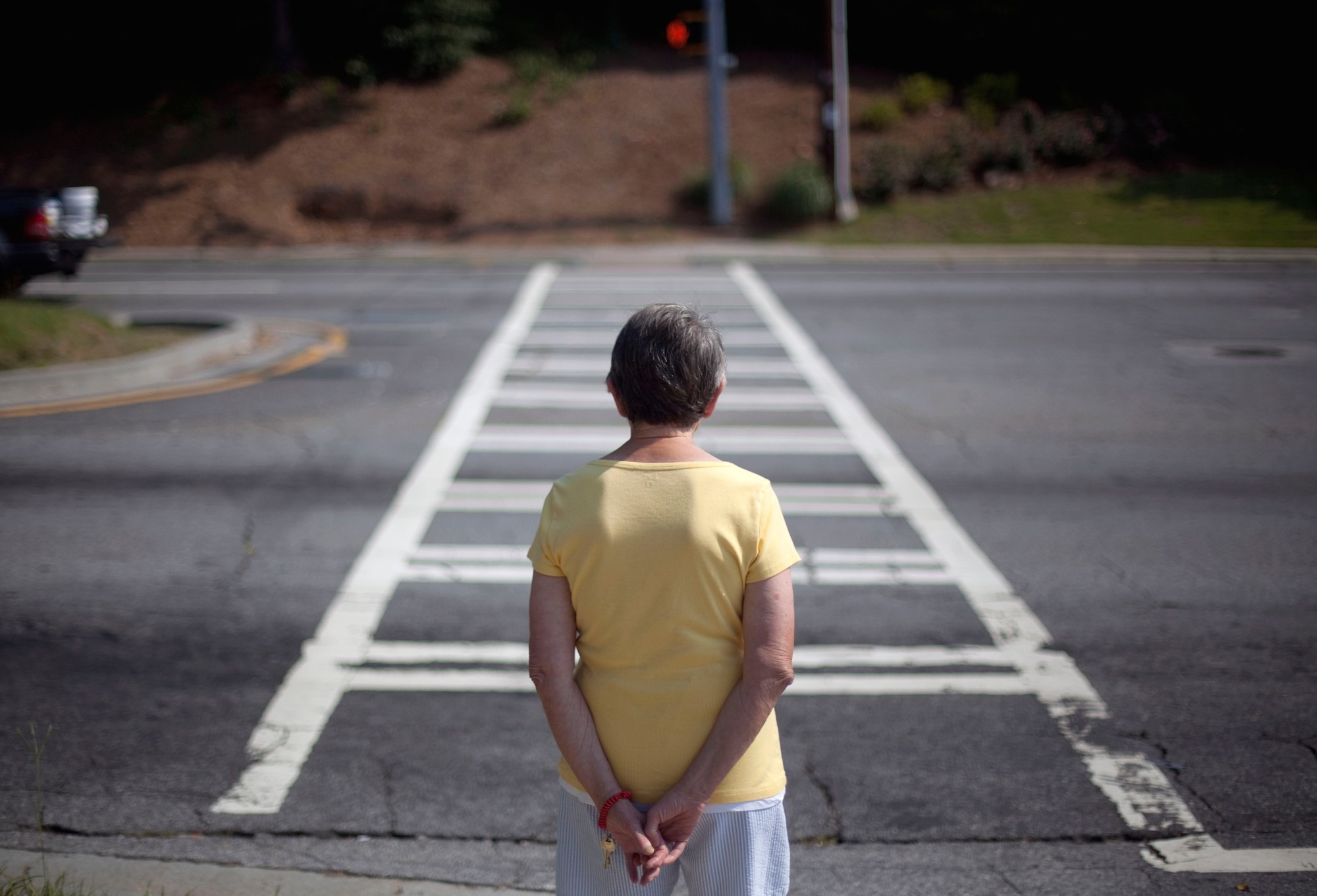 A resident of the Marion Apartments at 760 Sidney Marcus Boulevard waits for the light to change to cross the street outside the building Wednesday, June 15, 2011 in Atlanta. America's cities are beginning to grapple with a fact of life: people are getting old, fast, and they're doing it in communities designed for the sprightly.  (AP Photo/David Goldman)