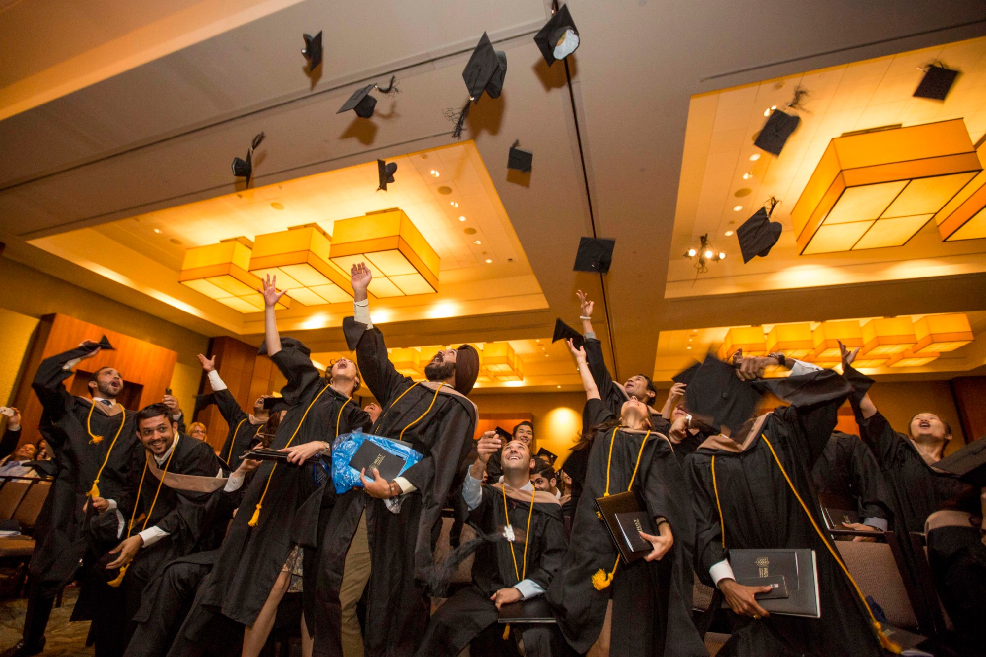 Graduates throw their caps at the conclusion of a commencement ceremony for business school, August 2016, in Boston. (AP/Scott Eisen)