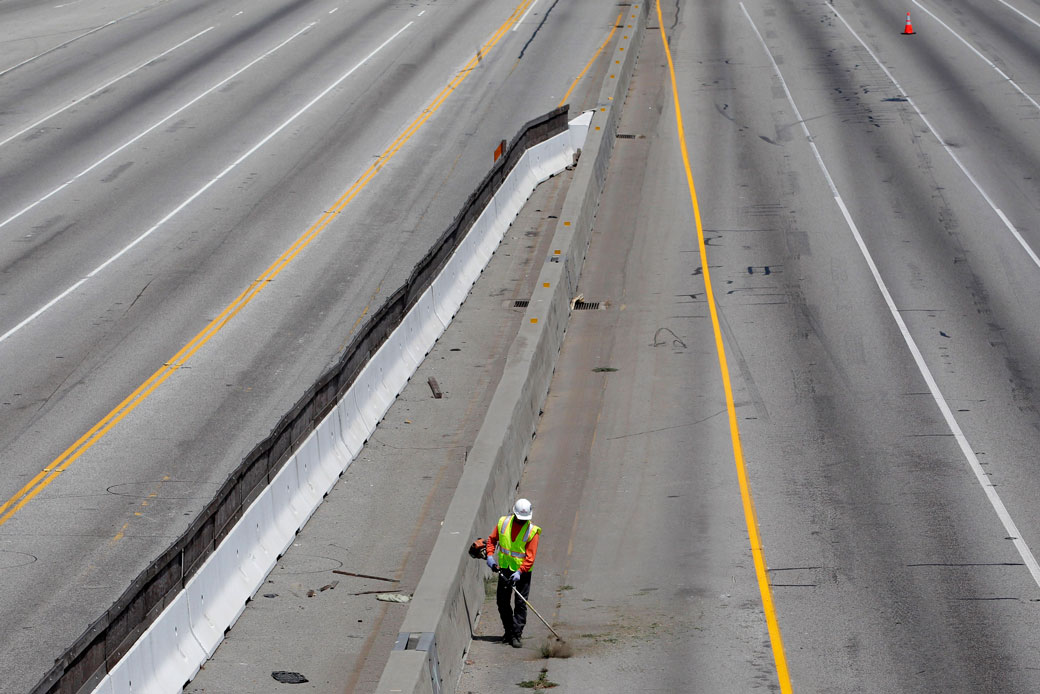 A worker cuts weeds growing along Interstate 405 in Los Angeles, July 16, 2011. (AP/ Jae C. Hong)