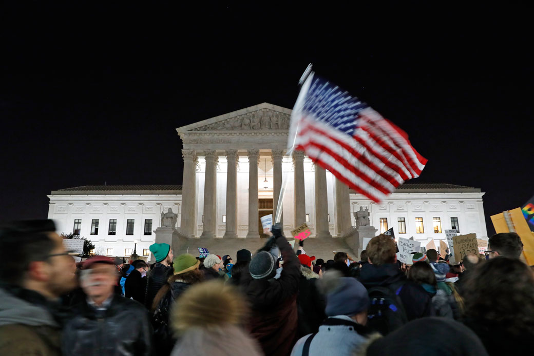 A protester waves an American flag in front of the Supreme Court during a protest about President Donald Trump's recent executive orders, January 2017. (AP/Alex Brandon)