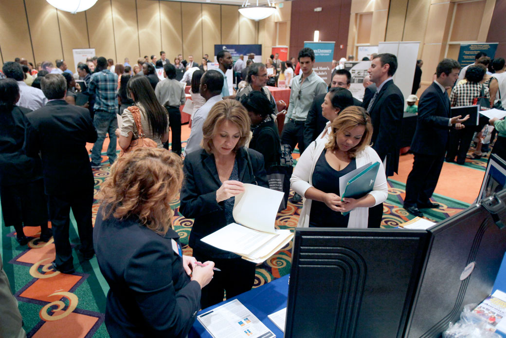 Job applicants visit various booths representing companies looking for employees or training schools at a job fair in Orlando, Florida. (AP/John Raoux)