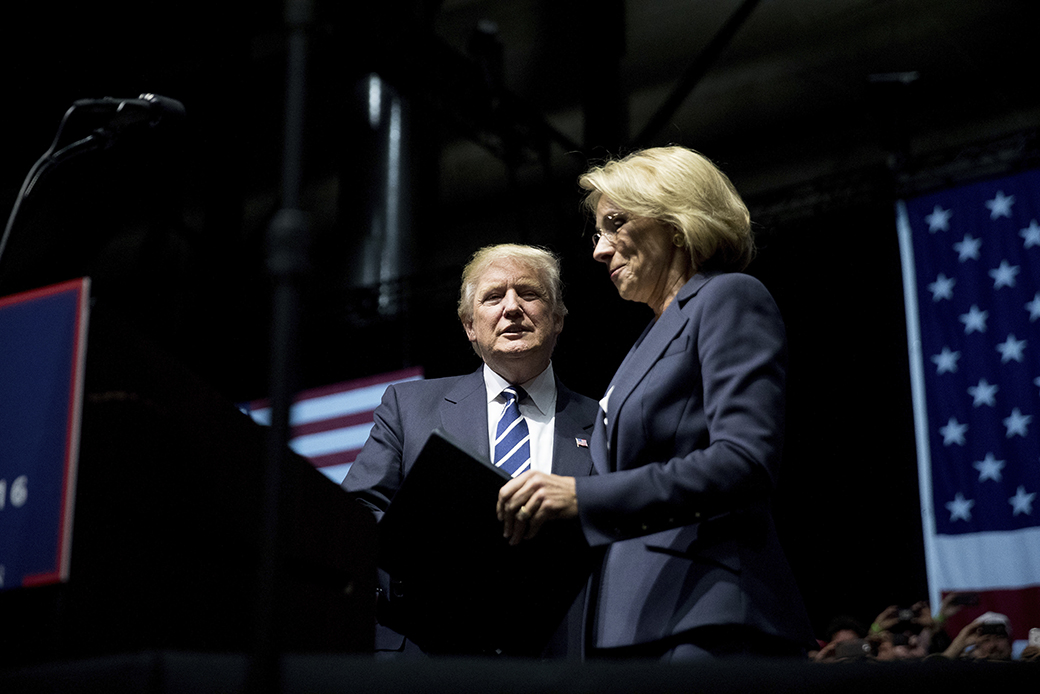 Then-President-elect Donald Trump, center, welcomes his pick for education secretary, Betsy DeVos, right, to the stage during a rally at DeltaPlex Arena, December 9, 2016, in Grand Rapids, Michigan. ((AP/Andrew Harnik))