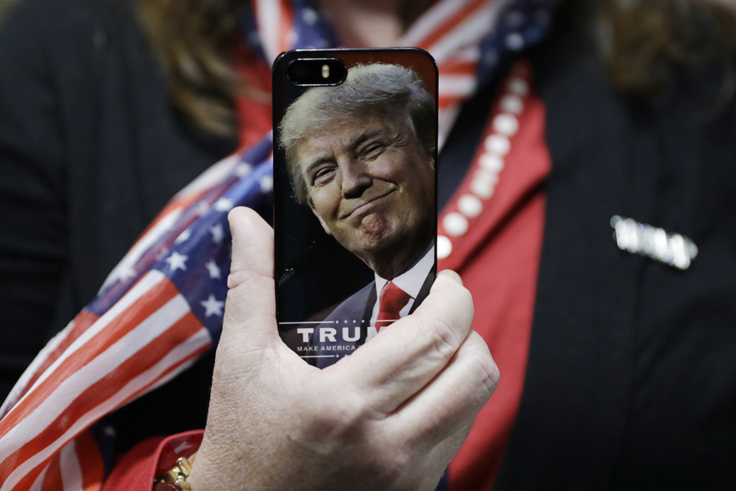 A woman holds up her cell phone before a rally with then-presidential candidate Donald Trump in Bedford, New Hampshire, September 29, 2016. ((AP/John Locher))