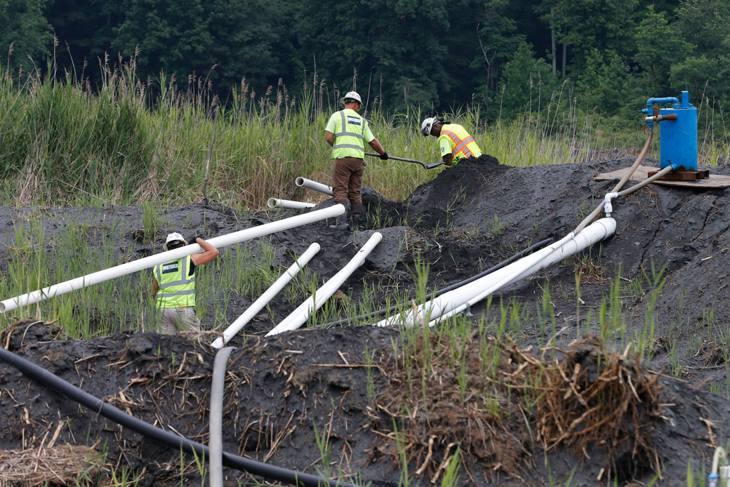 Workers install a drainage system in a coals ash retention pond at the Dominion Power's Possum Point Power Station in Dumfries, Virginia, on June 26, 2015. (AP/Steve Helber)