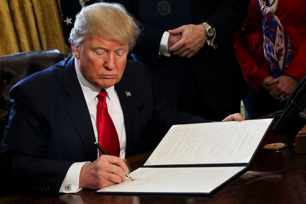 President Donald Trump signs an Executive Order in the Oval Office of the White House, to review the Dodd-Frank Wall Street to roll back financial regulations of the Obama administration on February 3, 2017. (AP/Aude Guerrucci)