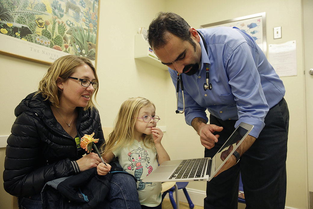 A pediatrician talks with a woman and her daughter during a medical checkup at a California clinic, February 2015. (AP/Eric Risberg)