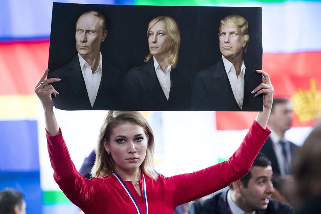 A journalist holds a poster with portraits of Russian President Vladimir Putin, left, France's far-right Front National President Marine Le Pen, center, and U.S. President Donald Trump prior to the Russian president's annual news conference in Moscow, December 23, 2016. ((AP/Pavel Golovkin))