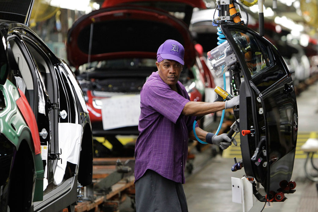 An assembly line worker moves a door into position at a General Motors assembly plant in Hamtramck, Michigan, July 27, 2011. (AP/Paul Sancya)