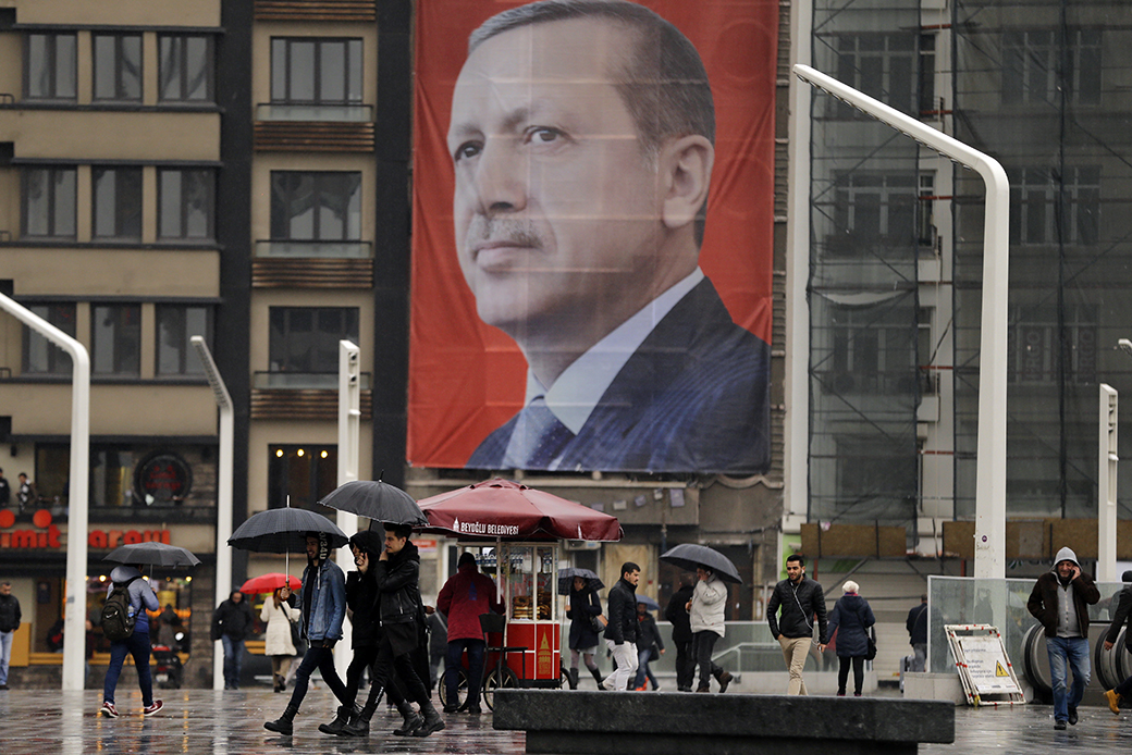 People walk in central Istanbul's Taksim Square, backdropped by a poster of Turkish President Recep Tayyip Erdoğan, March 14, 2017. (AP/Lefteris Pitarakis)