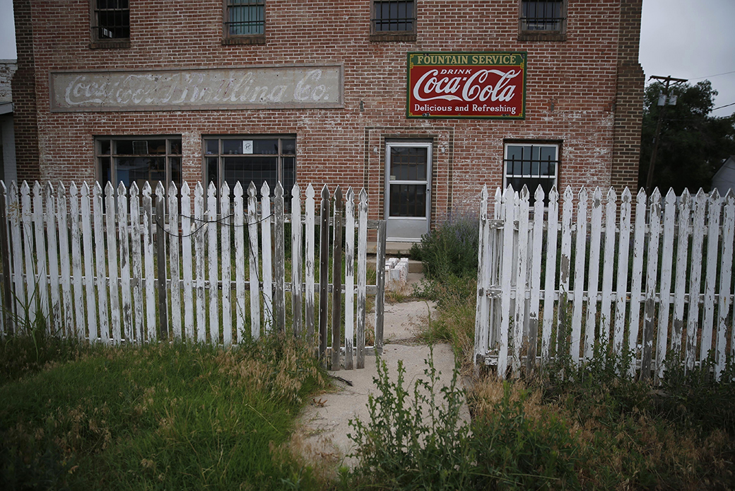 Weeds grow around an old building and picket fence in Rocky Ford, Colorado, on July 1, 2016. (AP/Brennan Linsley)